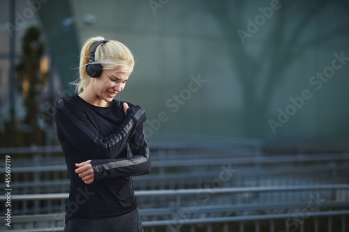 Young fitness woman feeling the pain in shoulder outdoor