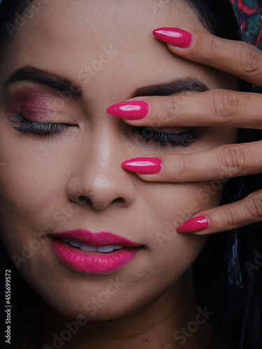 beautiful latina woman with dark complexion, with hands on her face showing beautiful coloured nails
