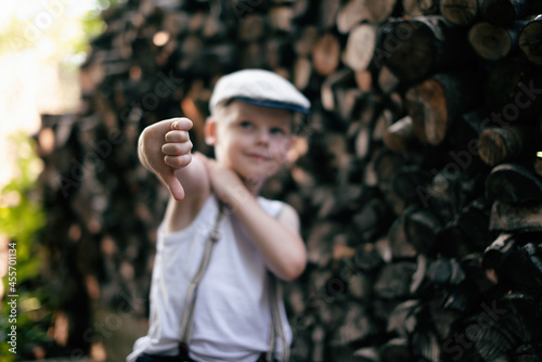 A small child poses against the background of sawn wood. Children's vacation in the countryside.