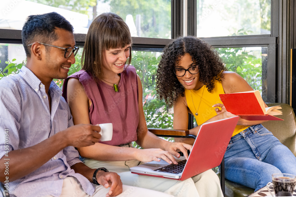 group of multiethnic students working in a public space, two young women and one man reading and having fun in a cafeteria, african american and caucasian people together around a laptop group of multiethnic students working in a public space, two young women and one man reading and having fun in a cafeteria, african american and caucasian people together around a laptop