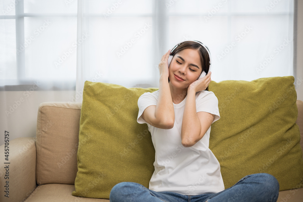 Relaxing time on sofa. Beautiful young asian woman sitting on sofa she choose music from smartphone take a rest and listening song with headphone. Lifestyle in living room at house in the morning. Relaxing time on sofa. Beautiful young asian woman sitting on sofa she choose music from smartphone take a rest and listening song with headphone. Lifestyle in living room at house in the morning.