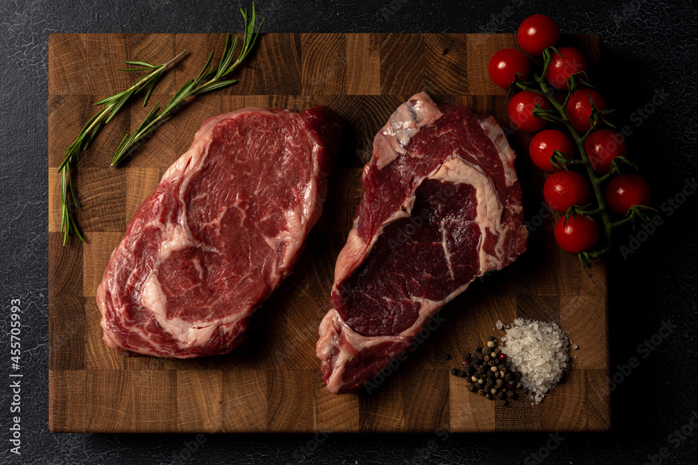 Raw marbled beef steak on a wooden cutting board. Top class marbled beef. Graphite-colored table top.