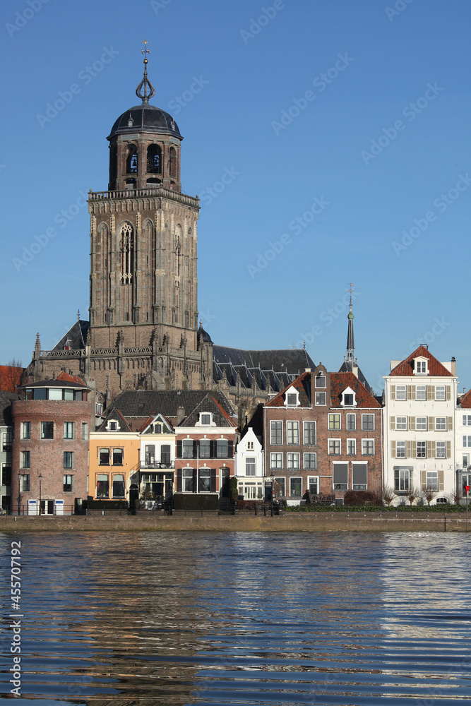 The facades of beautiful old buildings and the tower of the Great Church in the city of Deventer, The Netherlands, with reflection in the river IJssel