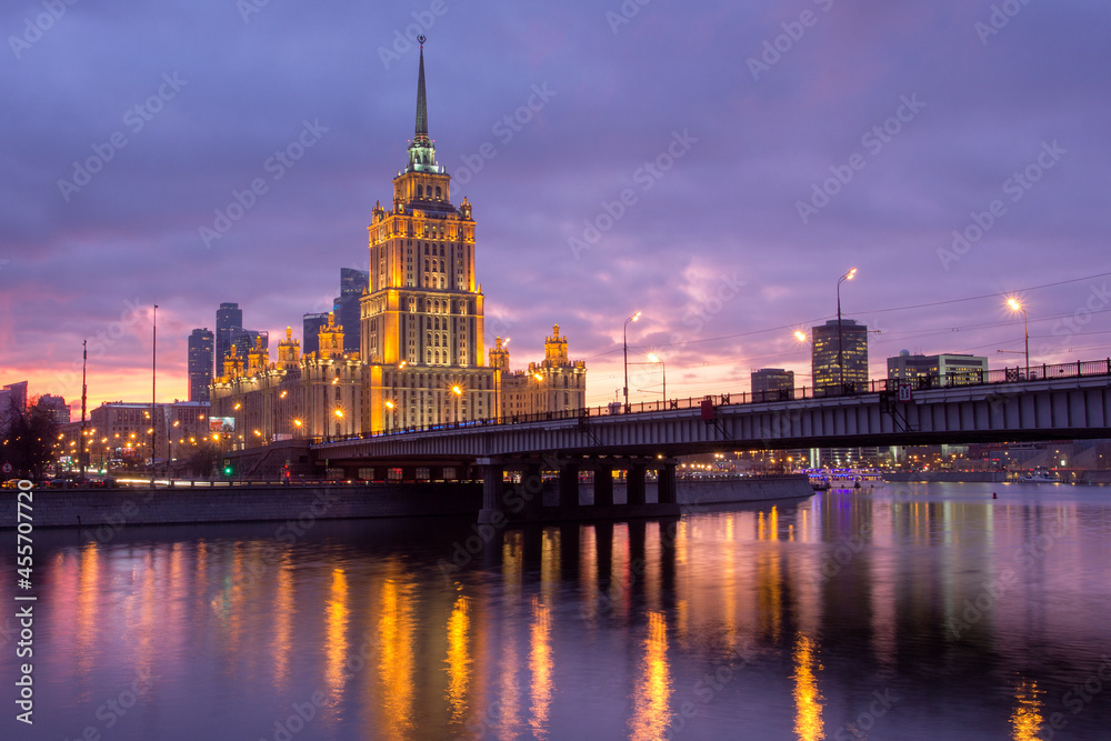 Naklejka premium Sunset on the river. Moscow Stalin-era skyscraper at sunset. Evening illumination.