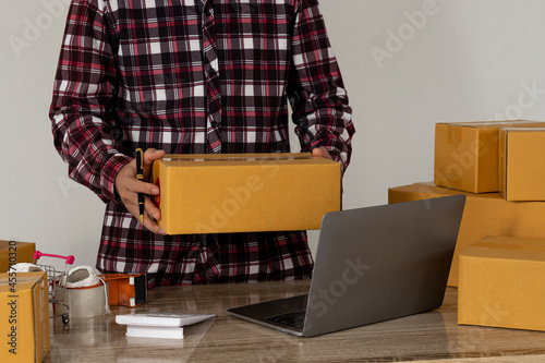 Start small business, independent SME entrepreneur, Asian woman working at home portrait with Boxes and laptops to receive orders from customers online, marketing, packaging, shipping, SME, ecommerce  © ArLawKa