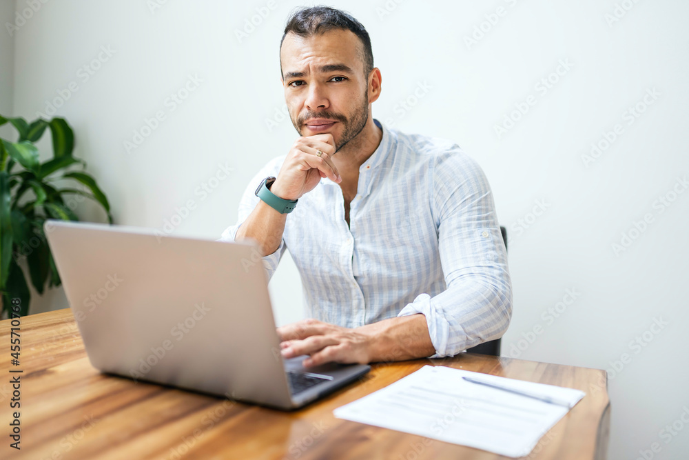 Portrait young mexican attractive businessman working at modern home office with computer laptop Portrait young mexican attractive businessman working at modern home office with computer laptop