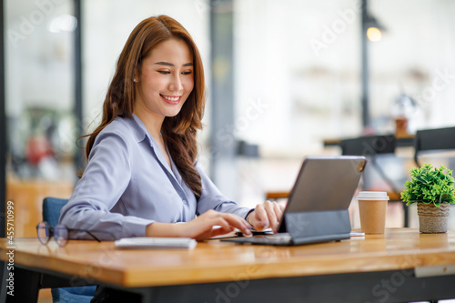 Portrait of smiling beautiful business asian woman with working in modern office desk using computer, Business people employee freelance online marketing e-commerce telemarketing concept.