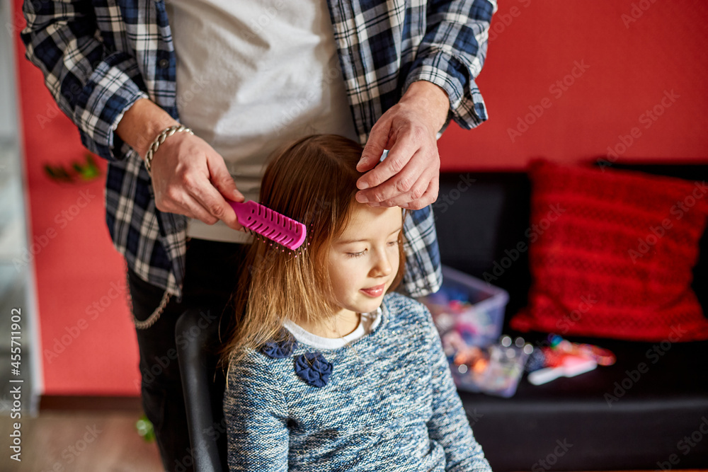 Father combing, brushing his daughter's hair at home