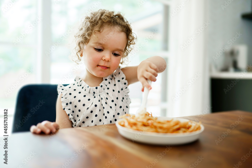 hungry little girl eating spaghetti at home kitchen
