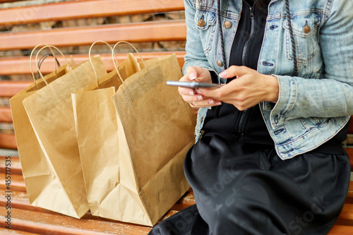 Woman sitting on the bench in the park withpaper shopping bags after shopping photo