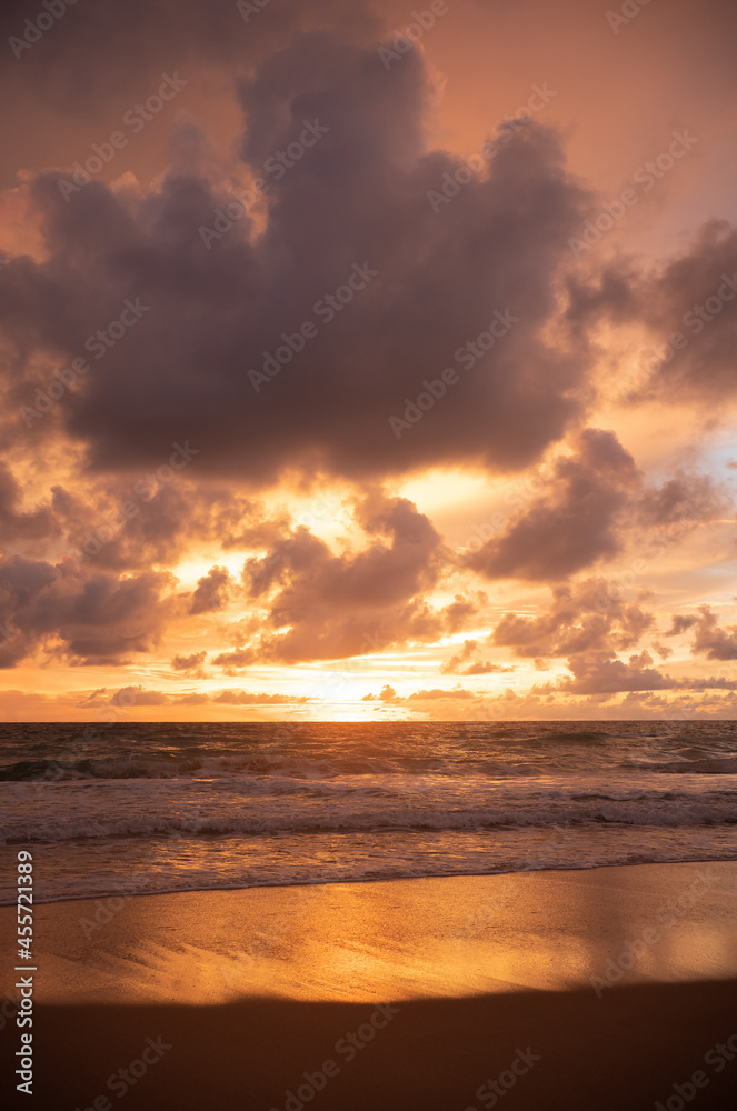 Sunset turquoise colored water on the beach.Orange sundown and golden sunset sky.Coconut trees on sun light and clouds background.
