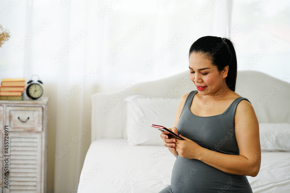 pregnant woman using mobile phone to check some news and search the knowledge about baby care in bed room. pregnant woman using mobile phone to check some news and search the knowledge about baby care in bed room.