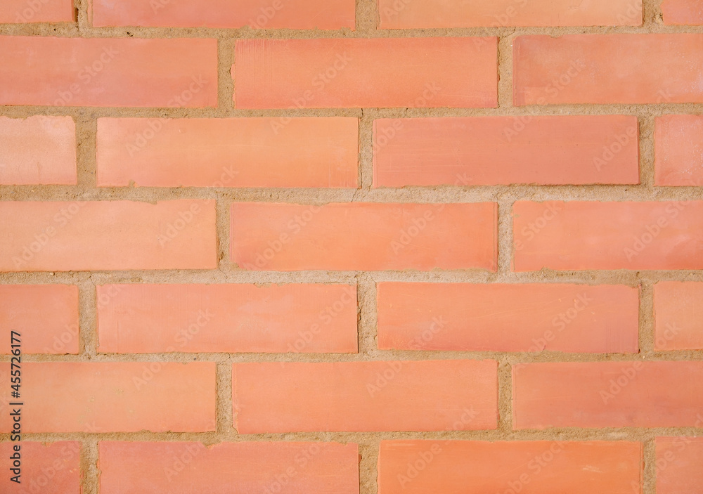 Obraz premium The brick wall of the fireplace is made of a red material, the seams of which are made of clay, and in some places cracks and damage are visible.