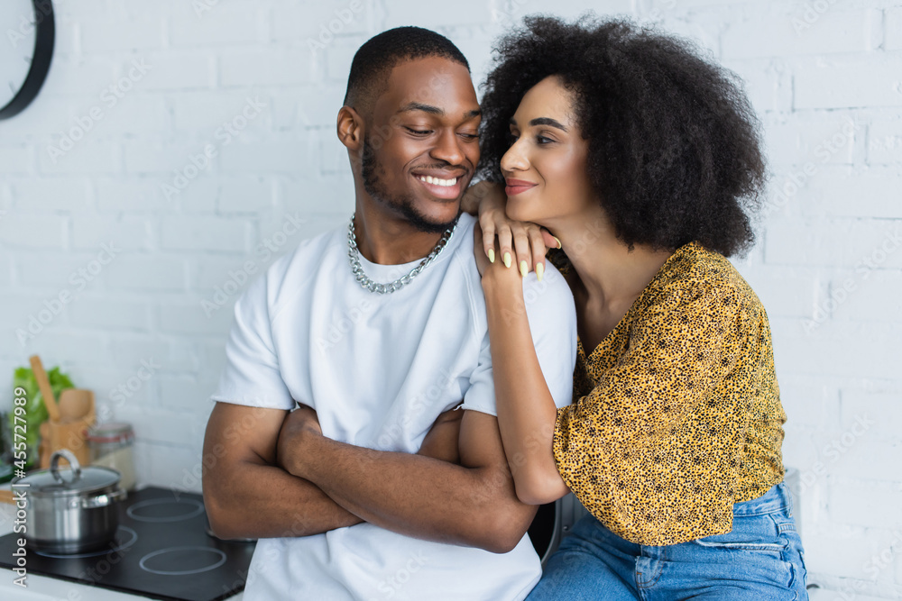 Obraz premium Young african american woman hugging smiling boyfriend at home.