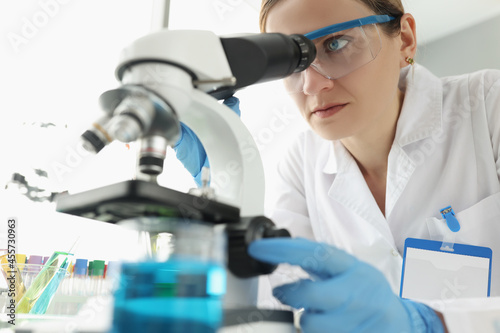 Portrait of female scientist looking through microscope in laboratory