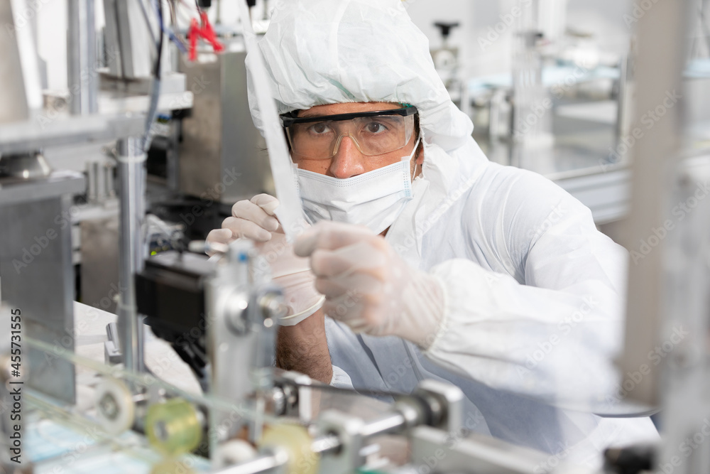 Naklejka premium male engineers wearing personal protective equipment uniform(PPE) and medical face mask, checking machine in laboratory