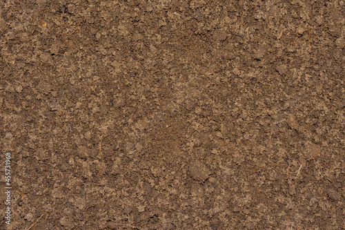 Background image of ground and sand close-up. Brown, wet soil.
