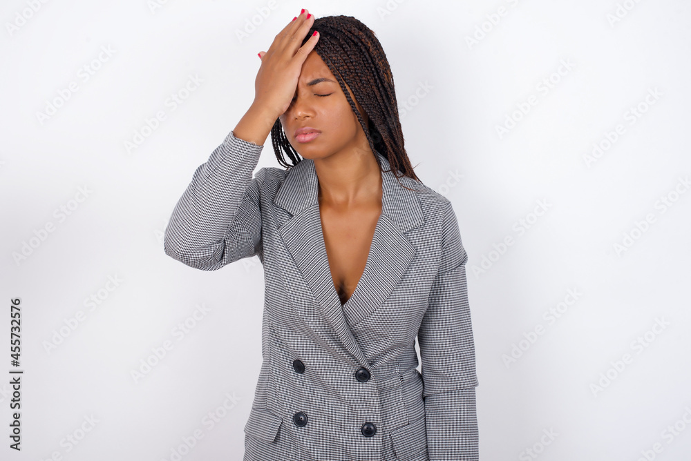 Frustrated Young african american business woman with braids over white wall holding hand on forehead being depressed regretting what he did having headache, looking stressful. Frustrated Young african american business woman with braids over white wall holding hand on forehead being depressed regretting what he did having headache, looking stressful.