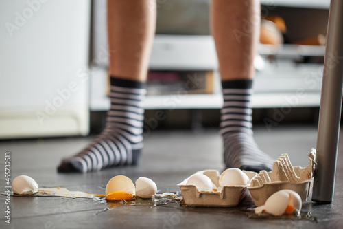Broken eggs - accident at kitchen, mess. Legs on background