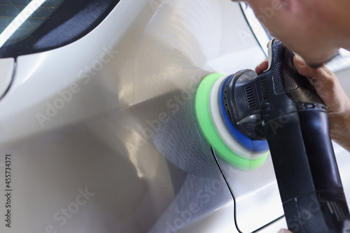 Man holds polisher in hand and polishes car closeup photo