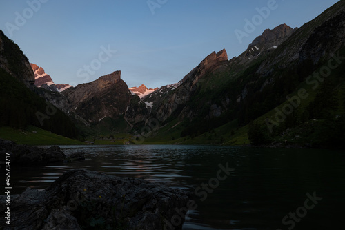 Epic sunrise by an alpine lake in Switzerland called Seealpsee. The sun shines to the peak of the mountain on the other side of the lake. This looks so wonderful.