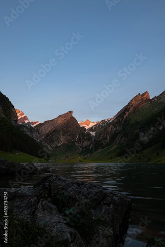 Epic sunrise by an alpine lake in Switzerland called Seealpsee. The sun shines to the peak of the mountain on the other side of the lake. This looks so wonderful.