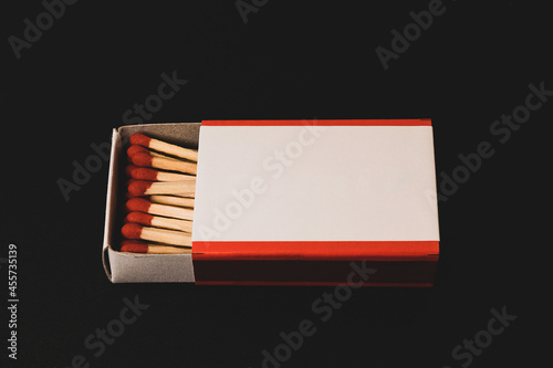 An open matchbox with a blank white label on a black table