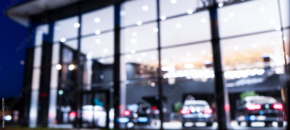 Blurred background with car dealership exterior. Abstract blurred photo of modern building motor showroom. Blur car show room office bokeh lights. Automobile retail shop - obrazy, fototapety, plakaty 