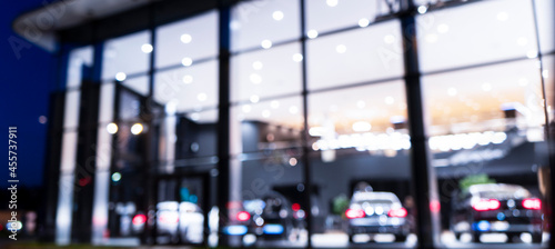 Blurred background with car dealership exterior. Abstract blurred photo of modern building motor showroom. Blur car show room office bokeh lights. Automobile retail shop photo