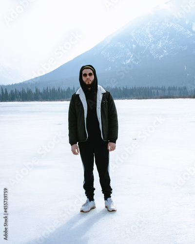 Man wearing jacket and sunglasses standing on snow-covered ground photo