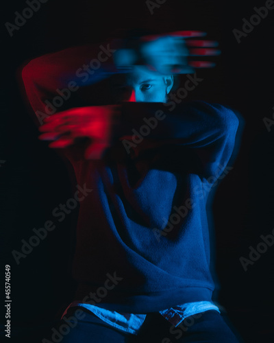 Portrait of man wearing sweater and collared shirt in red dim lit room photo