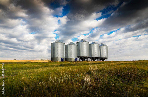 Grain silos standing tall on a harvested wheat field under a dramatic sky in Rockyview County Alberta Canada © Ramon Cliff