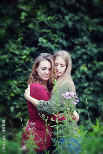 two young woman standing outdoors and hugging each other