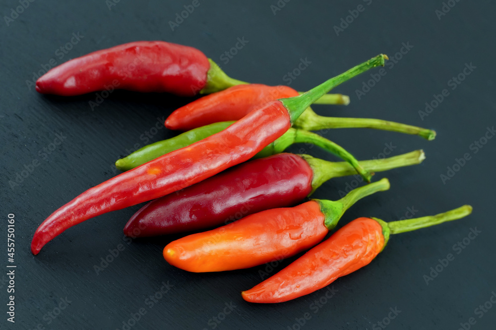 mini chili peppers bright red and orange pod lie in parallel on a black background
