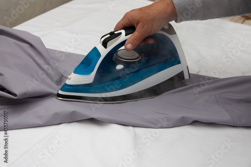 A nurse ironing a medical suit with an iron. From under which steam comes.