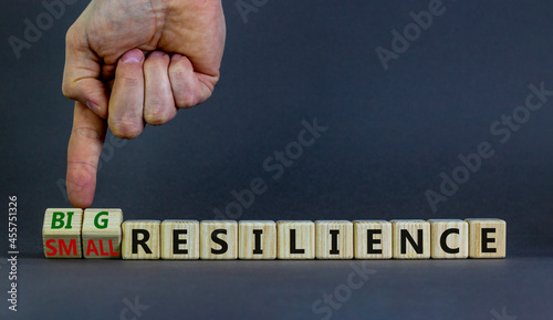 Big or small resilience symbol. Businessman turns wooden cubes, changes words small resilience to big resilience. Beautiful grey background, copy space. Business, big or small resilience concept.