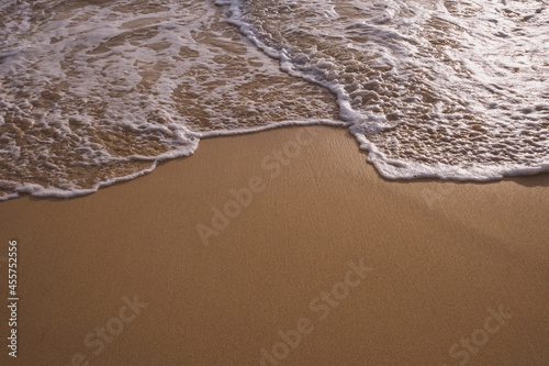 White boiling foam surf on the tropical sandy beach with copy space