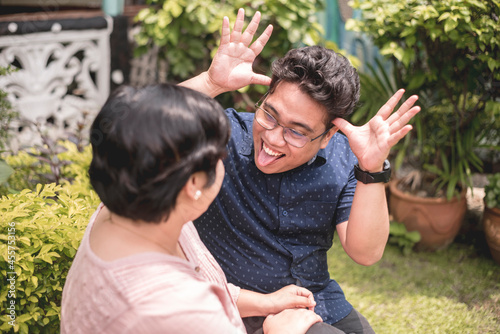 A silly filipino man teases his wife by sticking out his tongue. A fun relationship enjoying laughs and joking around.
