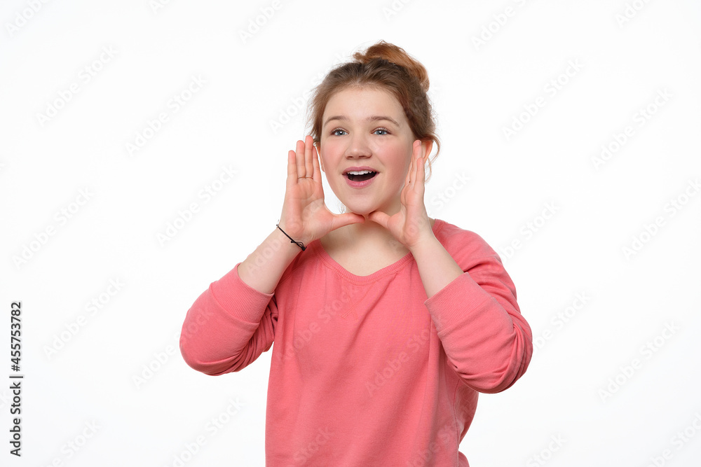 Attention, Good News. Beautiful young girl holding arms near open mouth and screaming, dressed in pink casual sweatshirt Attention, Good News. Beautiful young girl holding arms near open mouth and screaming, dressed in pink casual sweatshirt