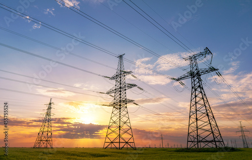 power line pylons during sunset with beautiful saturated sky. distribution transmission and consumption of electricity