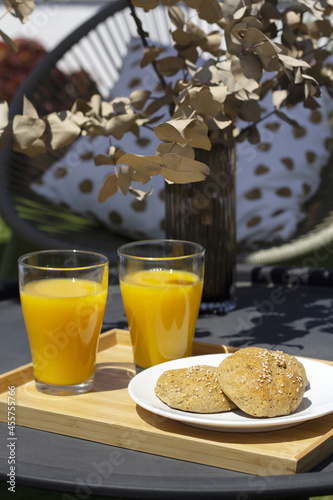 two orange juices and breads on a table in the hotel garden
