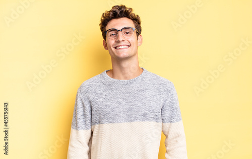 young teenager boy smiling cheerfully and casually with a positive, happy, confident and relaxed expression