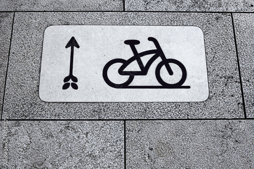 Bicycle sign and arrow on paving slabs in the park