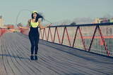 An attractive woman jumping rope on bridge