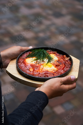 Crop young woman holding plate of shakshuka photo