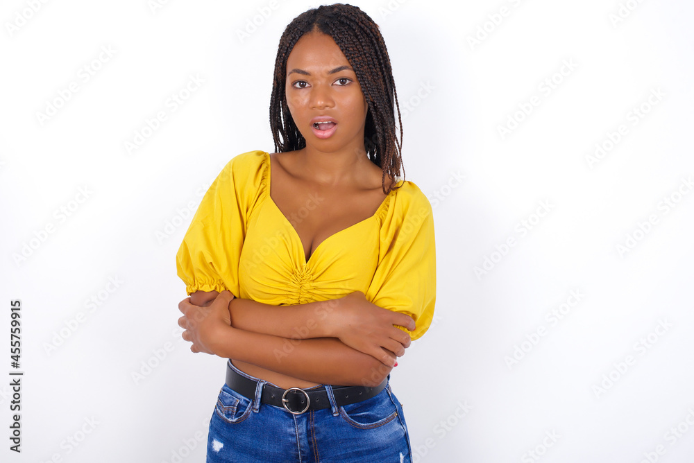Shocked embarrassed Young african american woman with braids over white wall keeps mouth widely opened. Hears unbelievable novelty stares in stupor Shocked embarrassed Young african american woman with braids over white wall keeps mouth widely opened. Hears unbelievable novelty stares in stupor