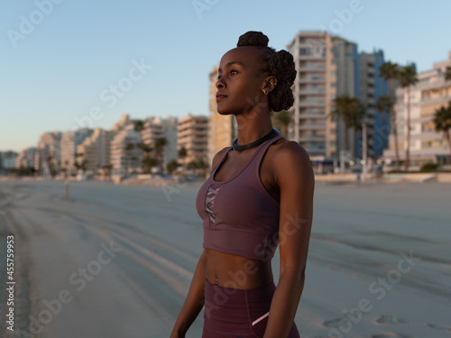 Black sportswoman standing on beach