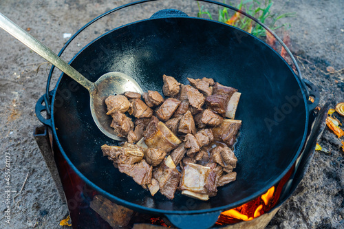 The initial stage of cooking pilaf - fried meat in a cauldron.
