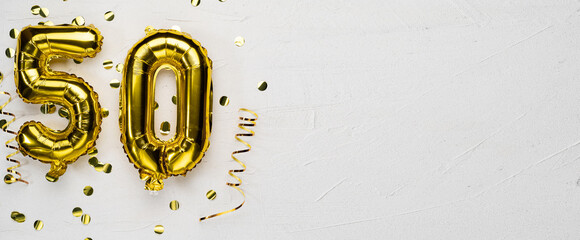 golden foil balloon number fifty. Birthday or anniversary card with the inscription 50. gray concrete background.
