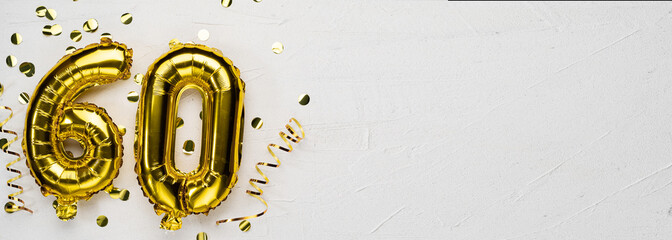 golden foil balloon number sixty. Birthday or anniversary card with the inscription 60. gray concrete background.